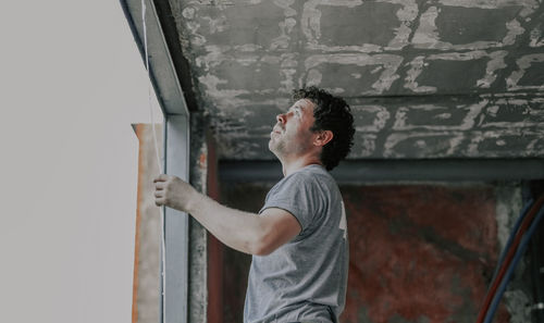 Young caucasian man removes a silicone rubber band from a window opening