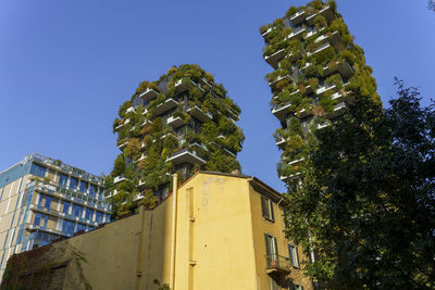 Low angle view of plants against building against clear blue sky