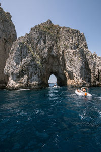 Rock formation in sea against clear sky