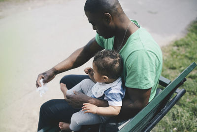 High angle view of father and son sitting on bench by road