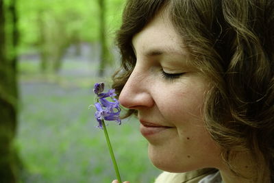 Close-up side view of smiling woman smelling flower