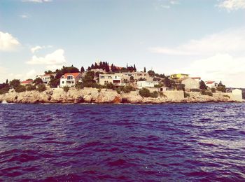 Buildings by sea against sky