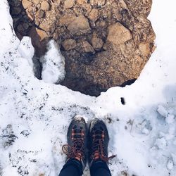 Low section of person standing on snowcapped mountain