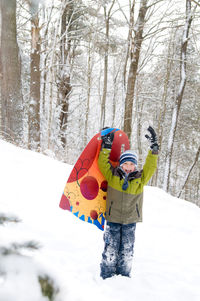 Boy with umbrella on snow covered trees during winter
