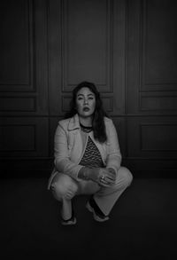 Portrait of young woman sitting by door