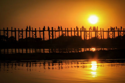 Silhouette pier over lake against sky during sunset