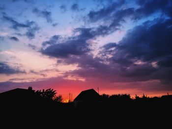 Silhouette trees and buildings against sky during sunset