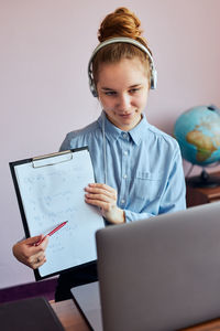 Cute girl showing clipboard while video conferencing