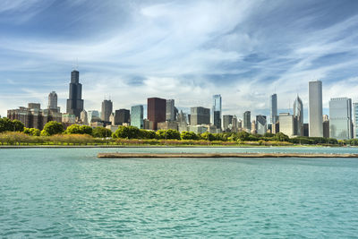 City at waterfront against cloudy sky