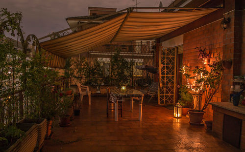 Chairs and tables by illuminated building against sky at night