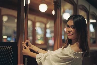 Portrait of woman looking at illuminated shop