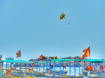 Woman flying over beach against clear sky