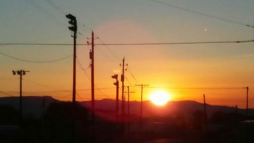 Low angle view of silhouette electricity pylon against sky during sunset