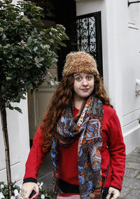 Portrait of woman wearing fur hat while standing by built structure