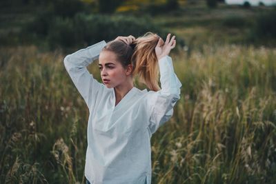 Young woman tossing hair while standing on field