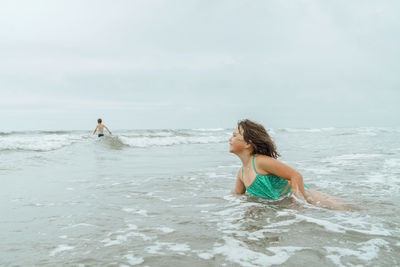 Woman enjoying at beach against sky