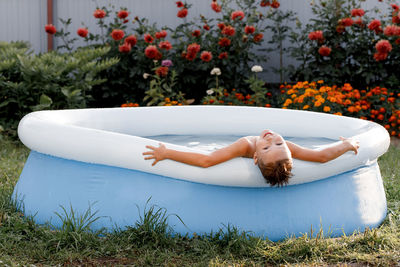 Image of a happy white boy lying in an inflatable pool and holding onto the side.