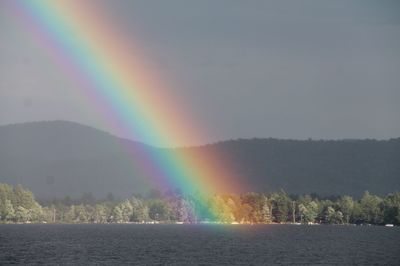 Scenic view of rainbow over lake against sky