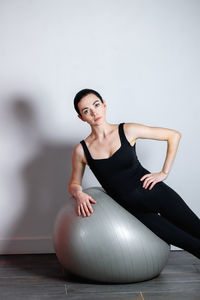 Portrait of young woman exercising with fitness ball