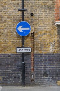 Close-up of road sign against brick wall