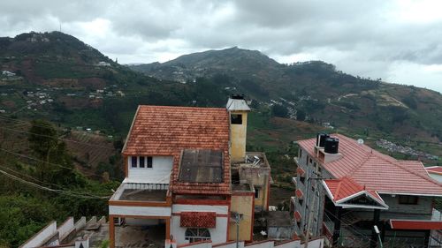 Houses on mountain against cloudy sky