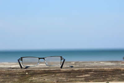 Close-up of sunglasses on beach against clear sky