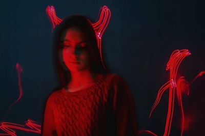 Young woman with red light painting in background at night