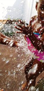 Midsection of woman splashing water in park