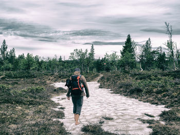 Rear view of man walking on road against sky