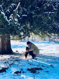 Man with dog on snow covered field