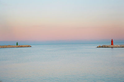 Sailboat sailing on sea against clear sky during sunset