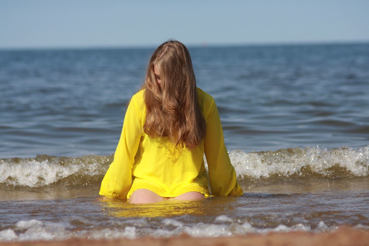 horizon over water, sea, water, beach, vacations, relaxation, weekend activities, tranquil scene, scenics, full length, long hair, selective focus, yellow, wave, tourist, nature, tranquility, escapism, shore, tourism, getting away from it all, beauty in nature, carefree, day, sky, seascape, summer, waterfront, human face, city life