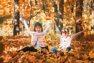 Cute kids playing amidst autumn leaves