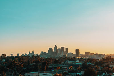 Buildings in city against clear sky during sunset