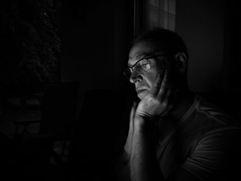 Thoughtful man in darkroom at home