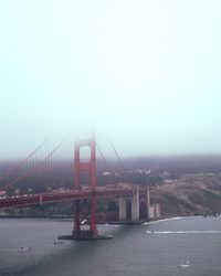 Suspension bridge over sea against clear sky