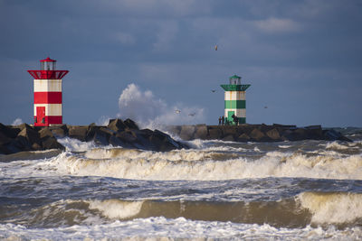 Lighthouse by sea against sky