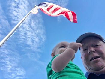 Low angle view portrait of boy and flags against sky