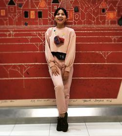 Portrait of young woman standing against wall