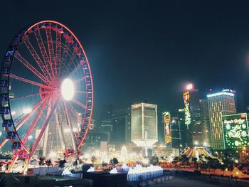 Illuminated ferris wheel in city at night