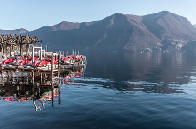 Sailboats moored in sea against mountains