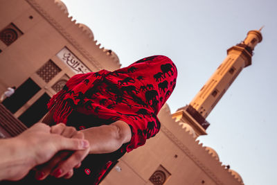 Low angle view of man holding red building against sky