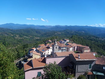 Scenic view of townscape and mountains against blue sky