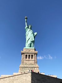 Low angle view of statue of liberty against blue sky