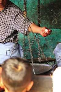 Rear view of boy looking at man holding ice cube over weight scale