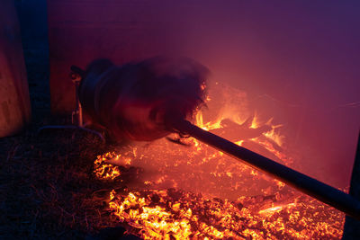 Silhouette of whole pig spinning on a spit