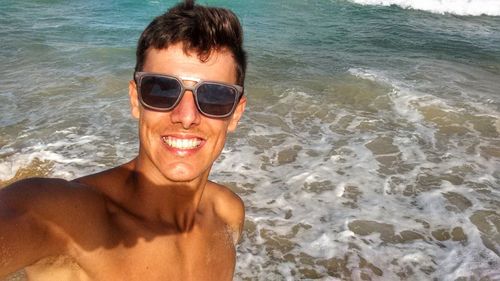 Portrait of man wearing sunglasses at beach