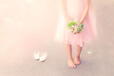 Low section of woman standing on pink flower