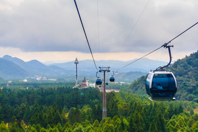 Overhead cable car over mountains against sky