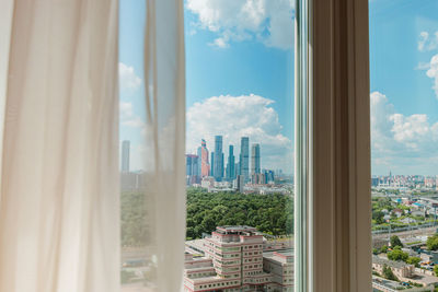 Buildings against sky seen through glass window